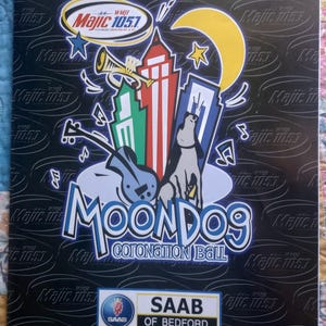 May include: A black promotional poster featuring a repeating Majic 105.1 logo pattern. The central graphic displays a colorful city skyline, a yellow crescent moon, a trumpet, a guitar, and a dog, with the text Moondog Coronation Ball and Saab of Bedford.