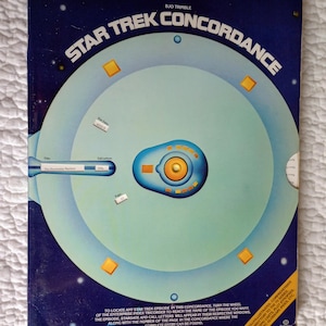 May include: A vintage "Star Trek Concordance" book cover. The cover features a blue and white graphic of a spaceship-like wheel with text that reads "Star Trek Concordance" and instructions for use. The book is a directory to the TV series.