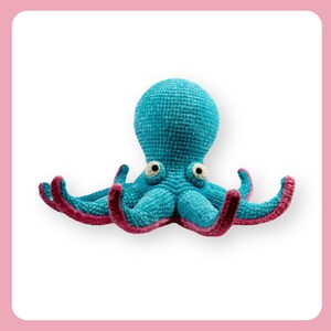 Puede incluir: Un juguete de peluche de pulpo tejido a crochet con un cuerpo azul y tentáculos rosas. El pulpo tiene ojos grandes y blancos.