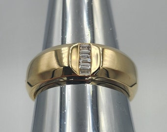 May include: A gold band ring with a single row of small, clear baguette-cut diamonds set in the center.