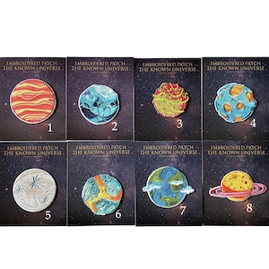 May include: Eight embroidered patches featuring different planets from the known universe. The patches are numbered 1 through 8. Each patch has a different color scheme and design.
