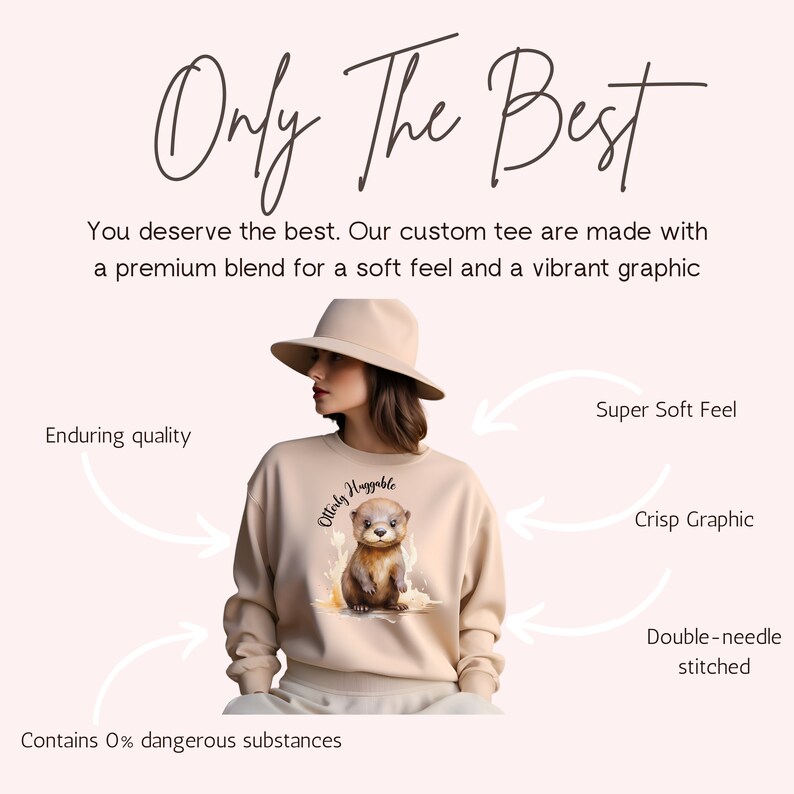 May include: A beige sweatshirt with a graphic of an otter wearing a crown and the text "Otterly Huggable". The sweatshirt is made with a soft, premium blend and features a double-needle stitched hem.