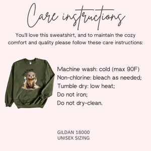 May include: A green sweatshirt with a graphic of a cute otter with the text "Pretty Nopable" on the front. The sweatshirt is made by Gildan and is unisex sizing. The care instructions are listed below: Machine wash: cold (max 90F) Non-chlorine: bleach as needed; Tumble dry: low heat; Do not iron; Do not dry-clean.