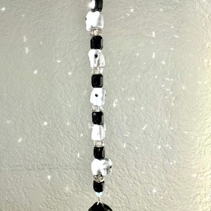 Peut inclure: Un attrape-soleil en cristal noir avec des éléphants en céramique blanche et des perles noires qui pendent.