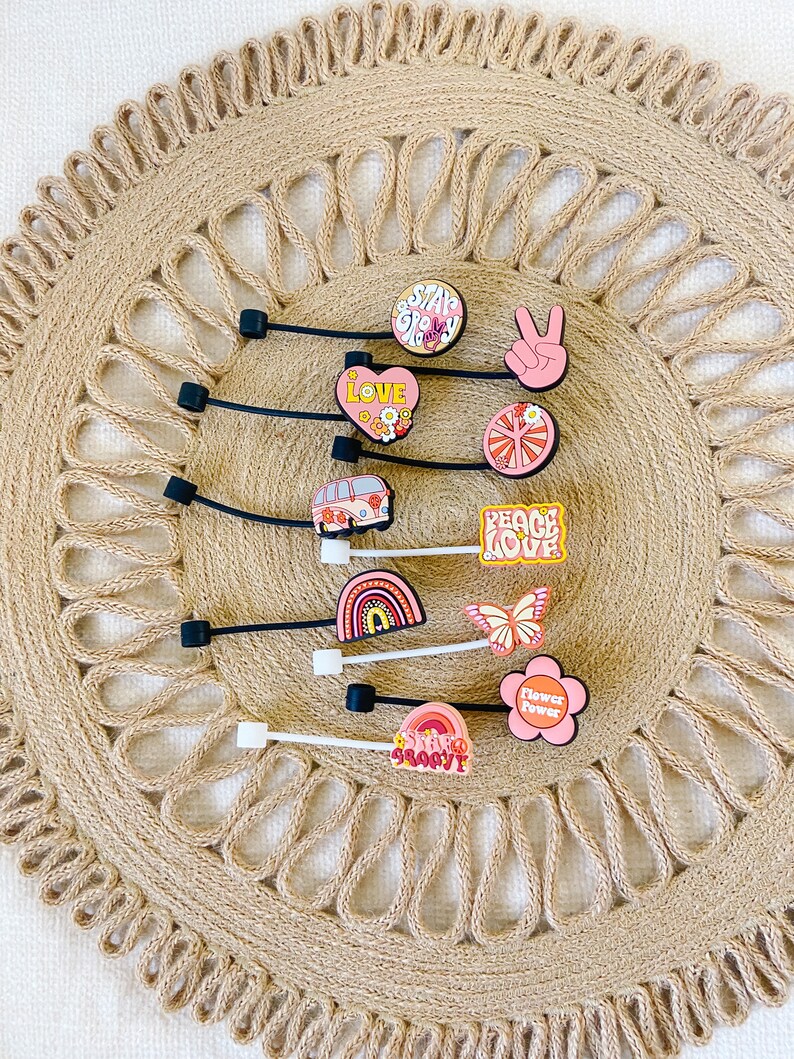 May include: A collection of colorful shoe charms with a retro, hippie theme. Designs include a peace sign, a rainbow, a butterfly, a flower, and the words "Love", "Peace Love", "Stay Groovy", and "Flower Power".