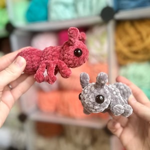 May include: Two crocheted plush ant toys. One is red and the other is grey. Both have large black eyes.