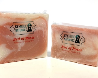 May include: Two bars of soap wrapped in plastic. The soap is pink and white and has a label that says "Keehole Naturals" and "Bed of Roses". The label also says "Rose and Copaiba Oils".