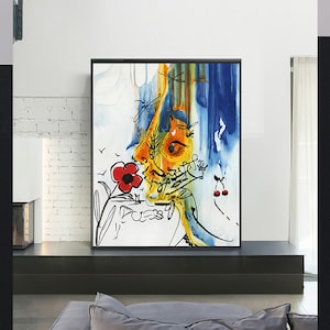 May include: Abstract watercolor painting of a face with a red flower and cherries. The painting is in a black frame and is hanging on a white brick wall.
