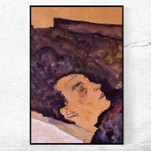 May include: A framed art print featuring a watercolor painting of a person's profile with closed eyes. The artwork uses a palette of muted colors, including shades of brown, purple, and peach. The person's hair is dark, and the background is a blend of colors.