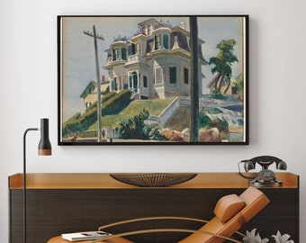 May include: Framed watercolor painting of a Victorian house on a hill. The house is painted in shades of white and beige with a purple roof. Green foliage surrounds the house and a utility pole is in the foreground. The painting is displayed above a brown cabinet.
