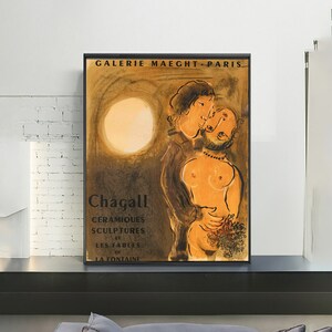 May include: A framed art print featuring a couple embracing, with a warm color palette. The print includes the text "GALERIE MAEGHT - PARIS" and "Chagall" along with other text. The artwork has a vintage aesthetic.