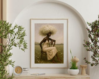 May include: Framed art print featuring a woman with a large, white, cloud-like afro, seated on a wooden chair in a field of flowers. She wears a cream-colored dress. The artwork has a soft, muted color palette and is displayed on a white wall.