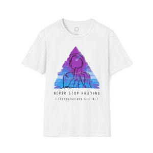 Puede incluir: Camiseta blanca con un diseño triangular de acuarela púrpura y azul que presenta un dibujo lineal de una persona rezando. El texto "NEVER STOP PRAYING" y "1 Thessalonians 5:17 NLT" está impreso debajo del diseño.