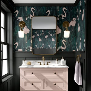 May include: A bathroom with a pink vanity, gold fixtures, and a marble countertop. The walls are dark green with a flamingo pattern wallpaper. A gold-framed mirror hangs above the vanity, and a white towel hangs on a gold ring.
