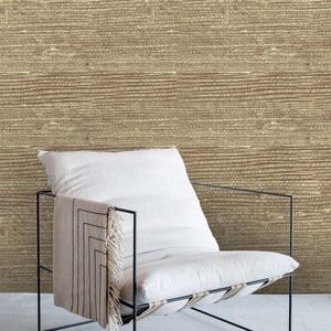 May include: A white chair with a black metal frame sits in front of a wall with a brown woven texture. The chair has a white cushion and a black and white throw draped over the back.