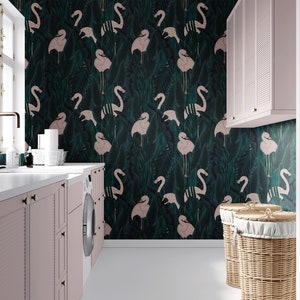May include: A laundry room with a flamingo-patterned wallpaper in shades of green and pink. The room features pink cabinets, a white countertop, a washing machine, and two wicker laundry baskets. A window and a gold faucet are also visible.