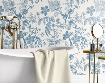 May include: A white bathroom with blue floral wallpaper, a white bathtub, a white towel, and a gold side table with a mirror and decorative bottles.