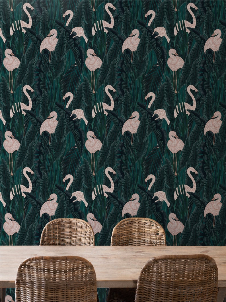 May include: Wallpaper featuring a repeating pattern of pink flamingos amidst dark green tropical foliage. The design includes large, stylized leaves and the birds are in various poses. The image also shows a wooden table and wicker chairs.