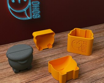 May include: Four 3D printed molds for making concrete planters. The molds are in the shape of a square, a round pot, and two different rectangular pots. The molds are orange and black. The molds are on a wooden surface. The text "BOHO 3D" is on one of the molds.