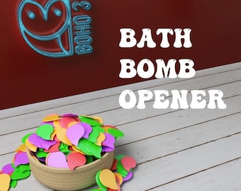 May include: A woven bowl overflowing with colorful, leaf-shaped confetti. The image features the text "BATH BOMB OPENER" and a logo with an owl design. The background is a mix of red and white wood.