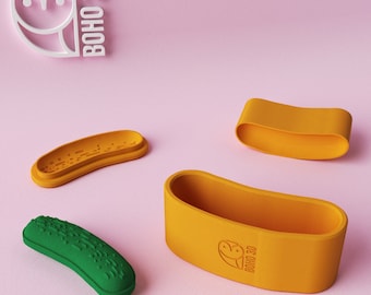 May include: A set of four 3D printed food-themed containers. The containers are shaped like a hot dog bun, a pickle, and two halves of a pickle. The containers are yellow and green and have the logo "BOHO 3D" printed on them.