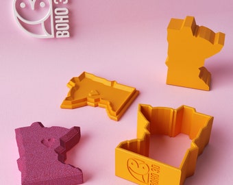 May include: Four 3D printed cookie cutters in the shape of the state of Minnesota. Two are yellow, one is pink, and one is yellow with the text "BOHO 3D" on the bottom.