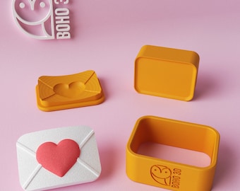 May include: Four 3D printed molds for making cookies or fondant decorations. The molds are in the shape of an envelope with a heart inside. The molds are orange and white. The molds are made by Boho 3D.