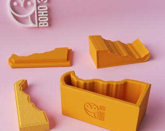 May include: Four pieces of a yellow 3D printed puzzle box with the logo "BOHO 3D" on the side. The box is made of multiple pieces that fit together to create a unique and decorative storage container.