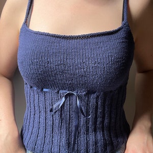 K&ouml;nnte beinhalten: Ein marineblaues Stricktop mit einem figurbetonten Oberteil und einer Schleife an der Taille.