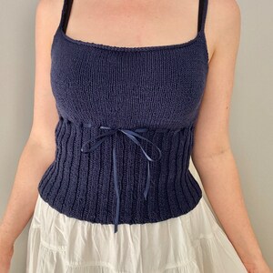 K&ouml;nnte beinhalten: Ein marineblaues Stricktop mit einem figurbetonten Oberteil und einer Schleife an der Taille.