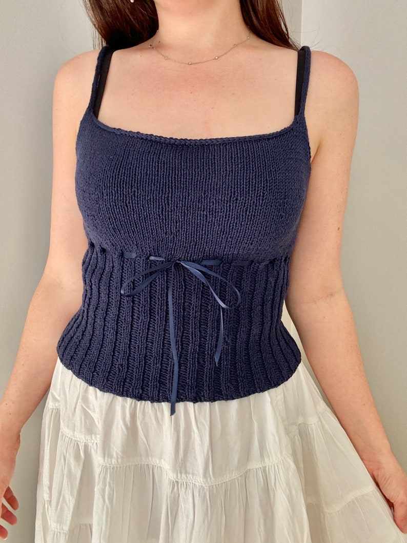 K&ouml;nnte beinhalten: Ein marineblaues Stricktop mit einem figurbetonten Oberteil und einer Schleife an der Taille.