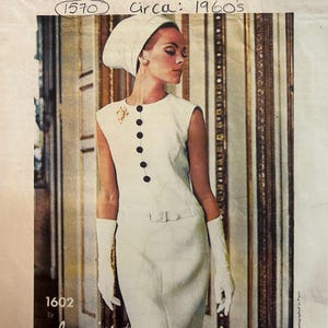 Puede incluir: Ilustración de moda vintage de Vogue Paris Original. La imagen presenta a una mujer con un vestido blanco con botones negros, un tocado a juego y guantes blancos largos. El texto incluye "Vogue Paris Original" y "Lanvin."