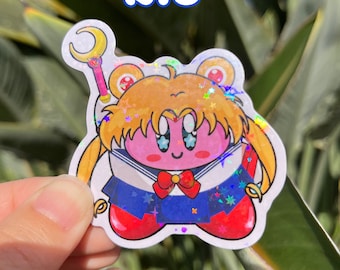 May include: A 2.5 inch holographic sticker featuring a pink and blue cartoon character with a sailor uniform, blonde hair, and a crescent moon wand. The character has large eyes with white stars inside. The sticker has a glittery finish.