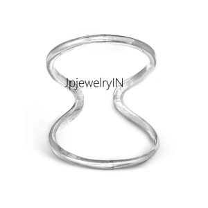 May include: A silver ring with a double band design. The ring is open on one side, creating a unique and modern look.