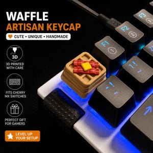 May include: A novelty waffle keycap on a mechanical keyboard. The keycap is a light brown colour, with a square pattern and a red and yellow topping. The keyboard keys are black with white and blue lettering.