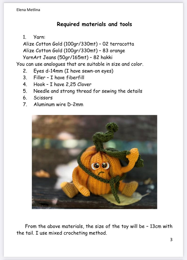May include: A crocheted pumpkin toy with a sad face, orange body, green stem, and brown eyes. The pumpkin is sitting on a wooden surface. The toy is 13 cm tall.