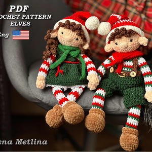 Puede incluir: Patrón de crochet PDF para dos elfos, uno con un vestido verde y medias a rayas rojas y blancas, el otro con pantalones verdes y una camisa a rayas rojas y blancas. Ambos elfos tienen el pelo castaño y llevan gorros rojos.
