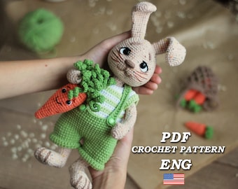 Könnte beinhalten: Häkelanleitung für einen niedlichen Hasen, der eine Karotte hält. Der Hase trägt ein grün-weiß gestreiftes Shirt und eine grüne Latzhose. Die Anleitung ist in englischer Sprache verfügbar.