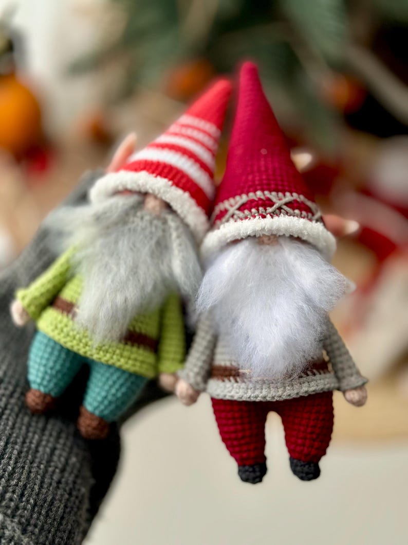 May include: Two crocheted gnomes, one with a red and white striped hat and green pants, the other with a solid red hat and red pants.