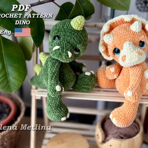 May include: Two plush crochet dinosaur toys, one green and one orange, sit on a wooden shelf. The green dinosaur has a green body with white accents and the orange dinosaur has white spots. The image includes text that reads "PDF CROCHET PATTERN DINO Eng".
