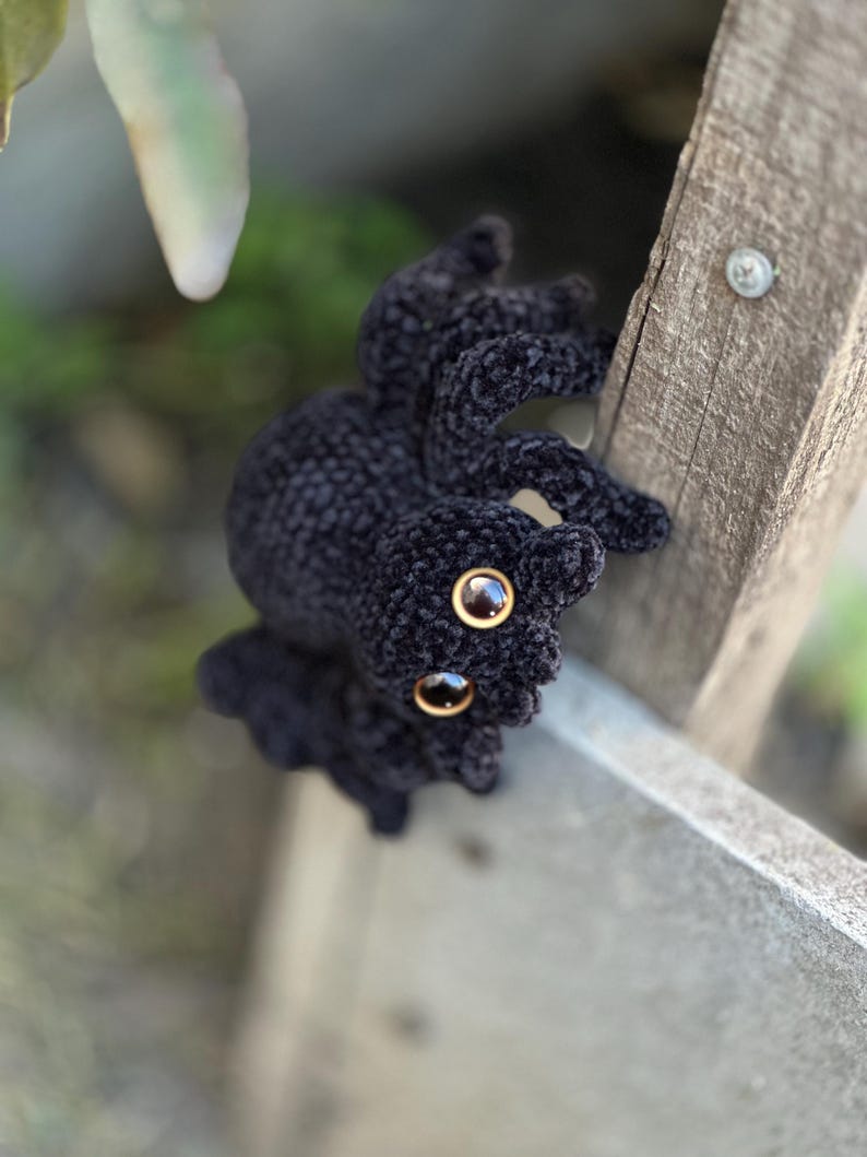 Peut inclure: Un crochet noir en forme d'araign&eacute;e avec de grands yeux ambr&eacute;s. L'araign&eacute;e en peluche a un aspect textur&eacute; et velout&eacute;. Les pattes de l'araign&eacute;e sont l&eacute;g&egrave;rement incurv&eacute;es, lui donnant une apparence r&eacute;aliste. Objet artisanal unique.