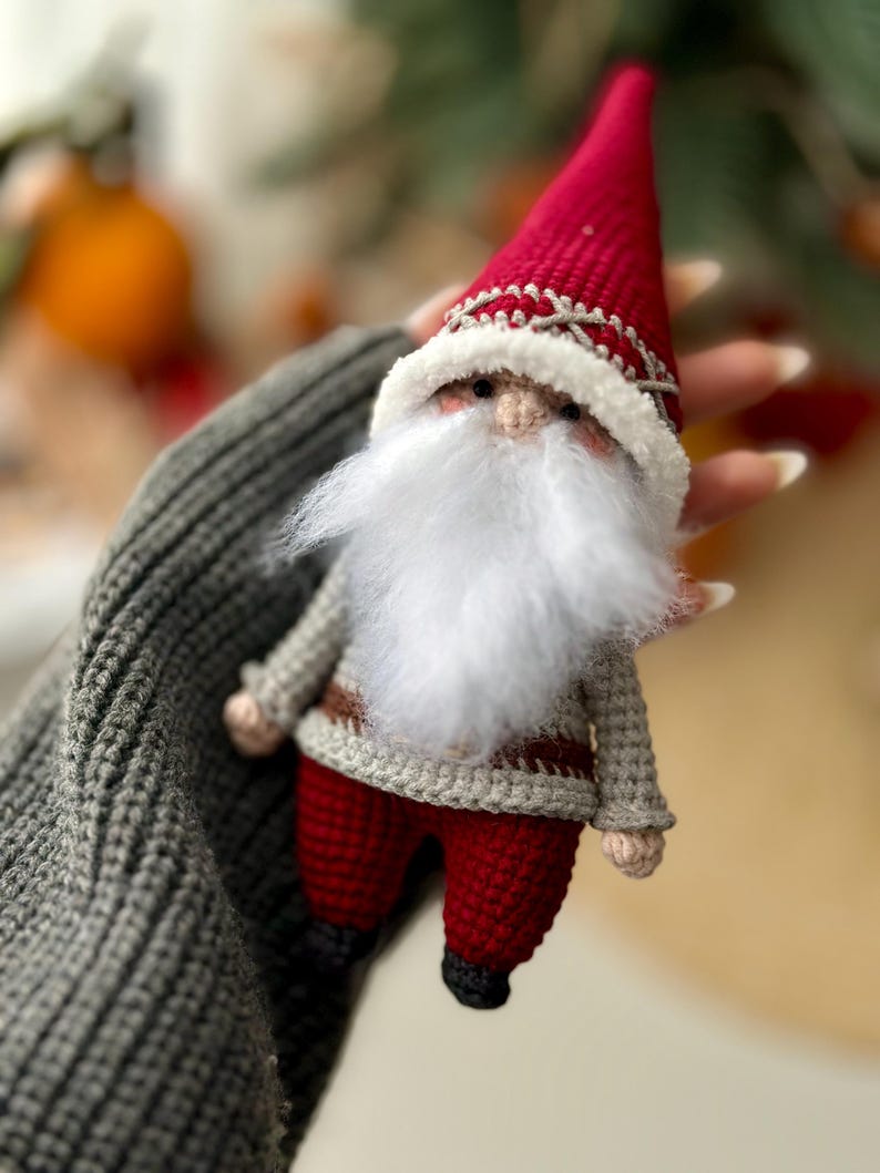 May include: A crocheted gnome ornament with a red hat, white beard, and gray and red clothing.