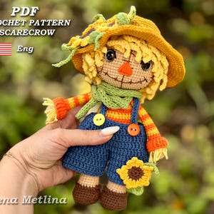 May include: A handmade crochet scarecrow doll with a yellow hat, straw-like hair, and a green scarf. The doll wears blue overalls with yellow and orange accents. The text "PDF CROCHET PATTERN SCARECROW Eng" is visible.