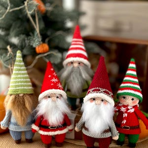 May include: Five crocheted gnomes in various colors and designs. The gnomes are wearing hats, scarves, and have white beards. They are standing on a brown burlap surface.