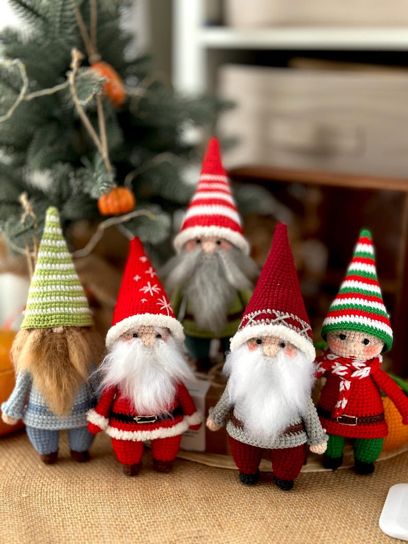May include: Five crocheted gnomes in various colors and designs. The gnomes are wearing hats, scarves, and have white beards. They are standing on a brown burlap surface.