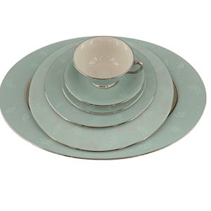 Può includere: Un set completo di porcellana fine in un colore verde acqua chiaro con finiture argentate. Il set include una tazza da tè, un piattino e diversi piatti di varie dimensioni, tutti adornati da un delicato motivo floreale. La tazza da tè è bianca all'interno.