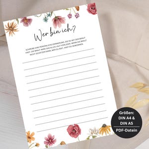 Op de afbeelding: Een printbare spelkaart met bloemenillustraties en de tekst "Wer bin ich?" De kaart heeft regels om te schrijven en instructies om een ​​persoonlijke herinnering over de bruid te schrijven. De kaart bevat ook de tekst "Größen: DIN A4 & DIN A5 PDF-Datein".