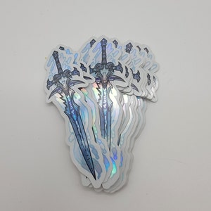 May include: A stack of holographic stickers featuring a blue and silver sword with a ram's head design. The sword is surrounded by a swirling blue and silver pattern.