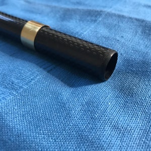 May include: A black carbon fibre rod with a gold ring near the end.