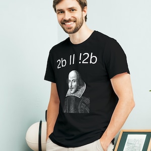 Puede incluir: Una camiseta negra con un gráfico blanco del retrato de William Shakespeare y el texto "2b || !2b".